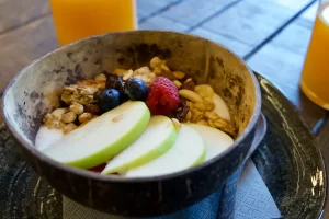 Tavolo con due aranciate e ciotola con muesli e frutta fresca