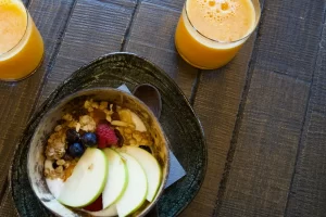 Tavolo con due aranciate e ciotola con muesli e frutta fresca