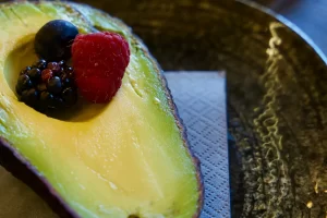 Piatto con mezzo avocado e frutti di bosco